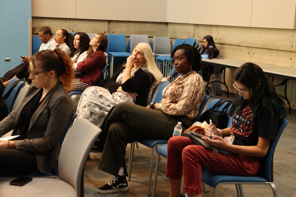 A diverse group of individuals sitting together in a well-lit room, engaged in a discussion or meeting.