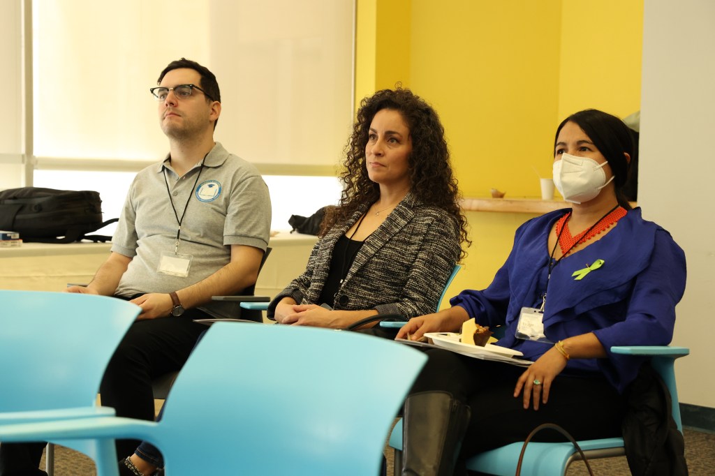 A diverse group of individuals sitting together in a well-lit room, engaged in a discussion or meeting.