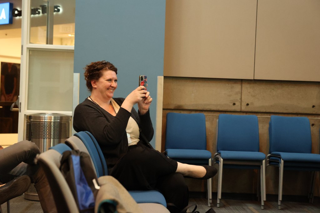 Light skinned woman, smiling while taking a photo