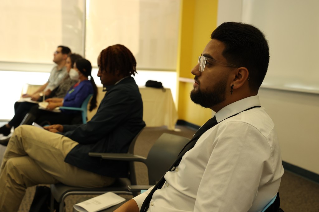 A diverse group of individuals sitting together in a well-lit room, engaged in a discussion or meeting.