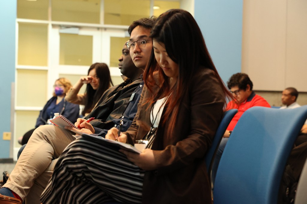 A diverse group of individuals sitting together in a well-lit room, engaged in a discussion or meeting.
