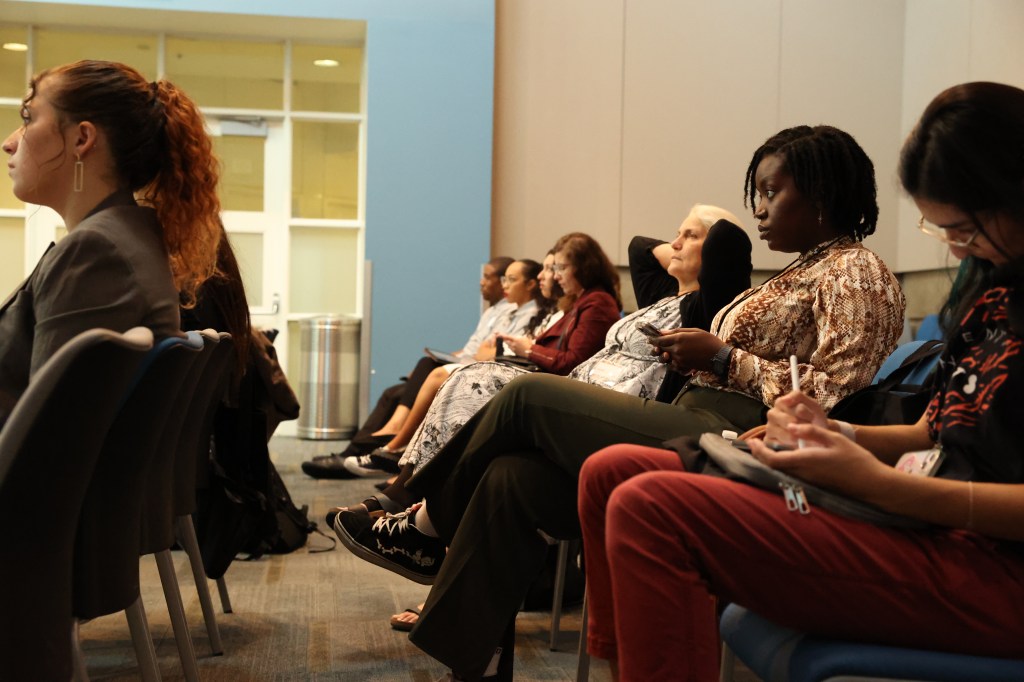 A diverse group of individuals sitting together in a well-lit room, engaged in a discussion or meeting.