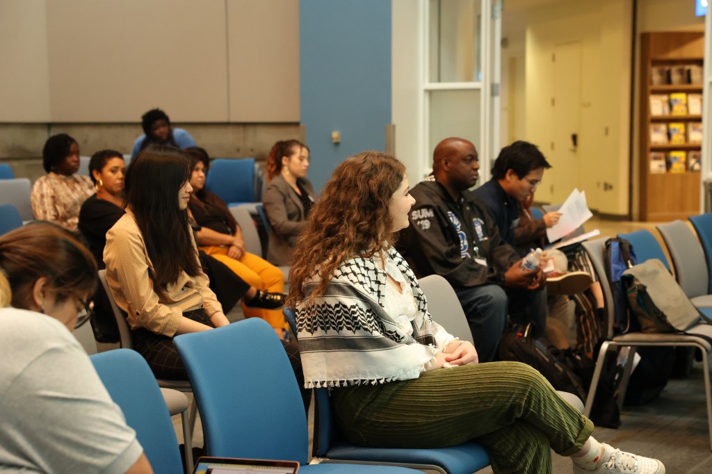 A diverse group of individuals sitting together in a well-lit room, engaged in a discussion or meeting.