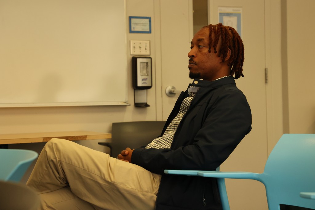 Fair-skinned man sitting in a room.