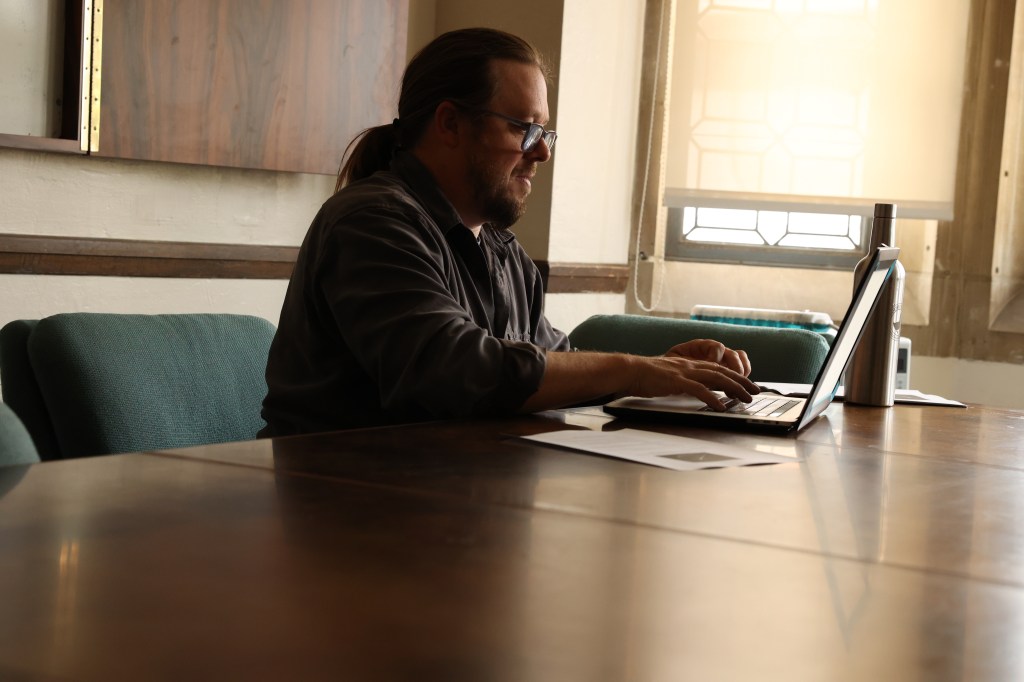 A man sitting while using his laptop