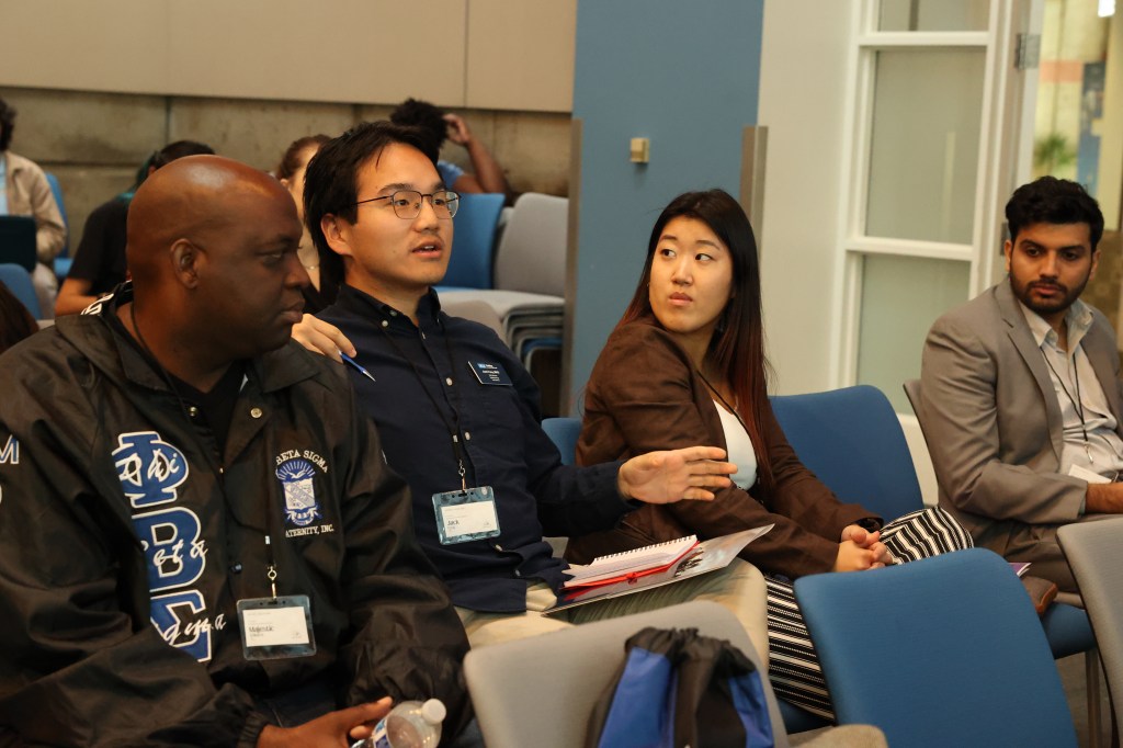 A diverse group of individuals sitting together in a well-lit room, engaged in a discussion or meeting.